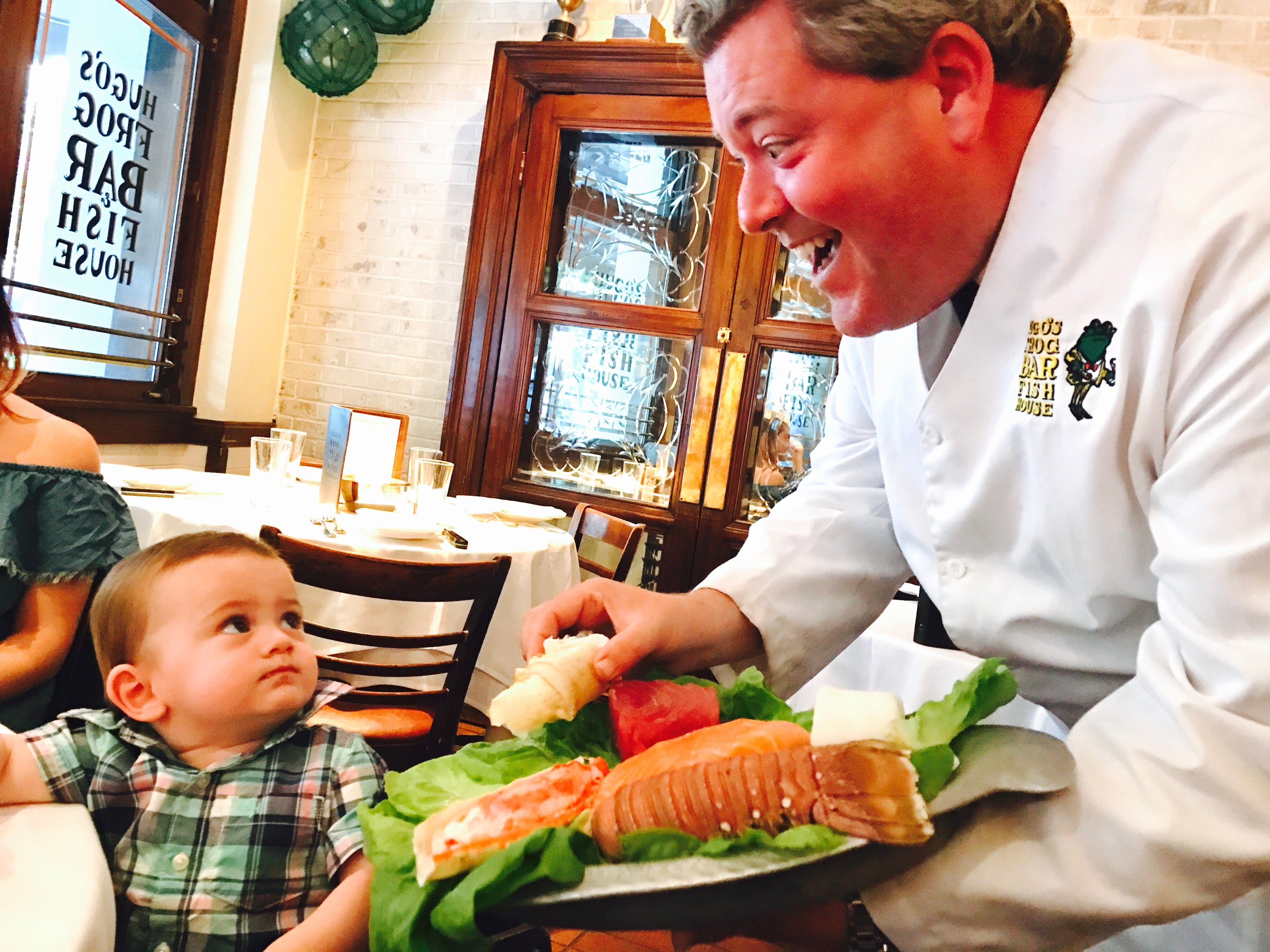 Server showing one year old baby boy lobster at a restaurant